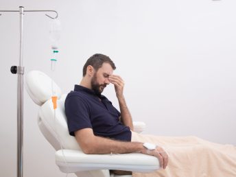 Sick, dehydrated or hangover patient man receiving vitamin IV infusion drip in hospital or beauty salon. Healthcare and medicine concept